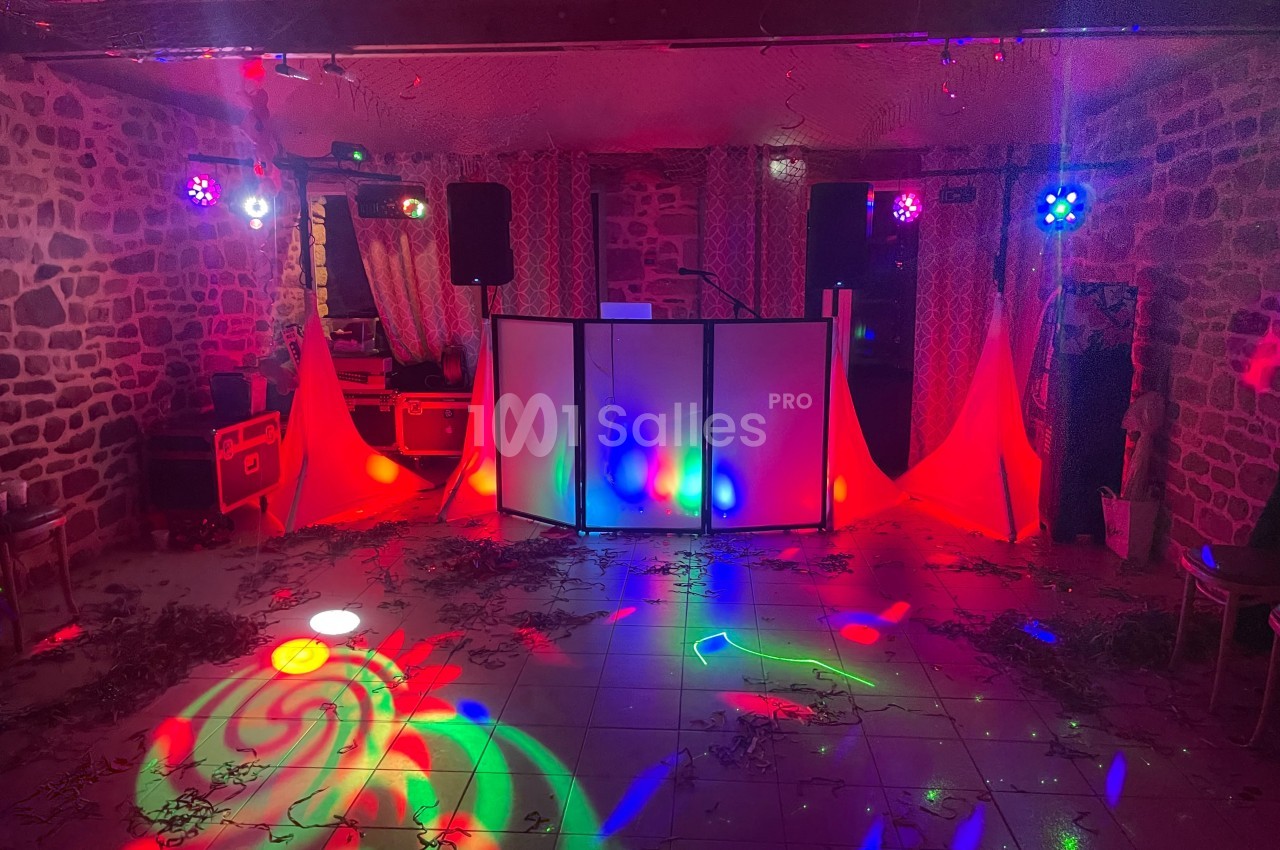 Salle de fête avec éclairage coloré, piste de danse illuminée et équipement de sonorisation installé.