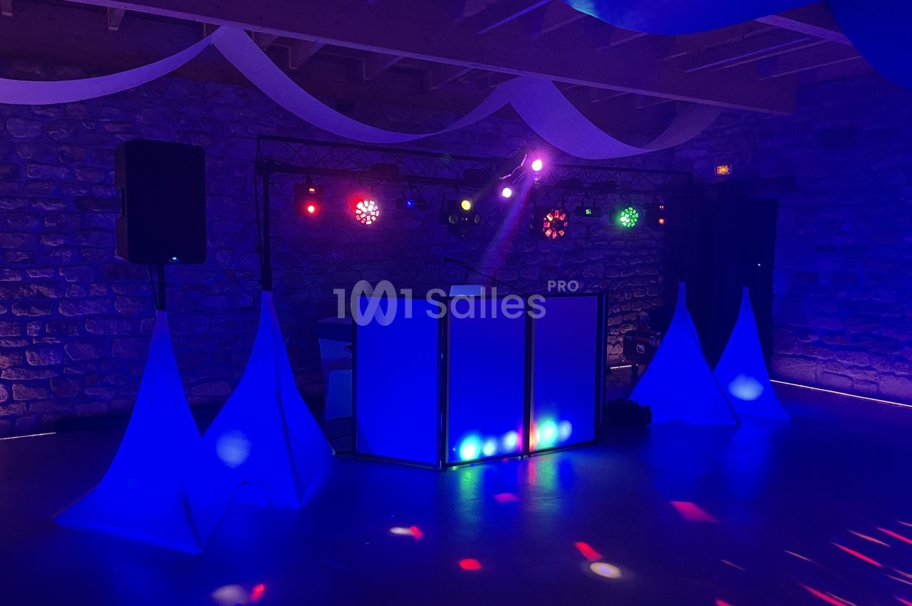 Installation de matériel de sonorisation et éclairage coloré dans une salle en pierre avec décorations suspendues.