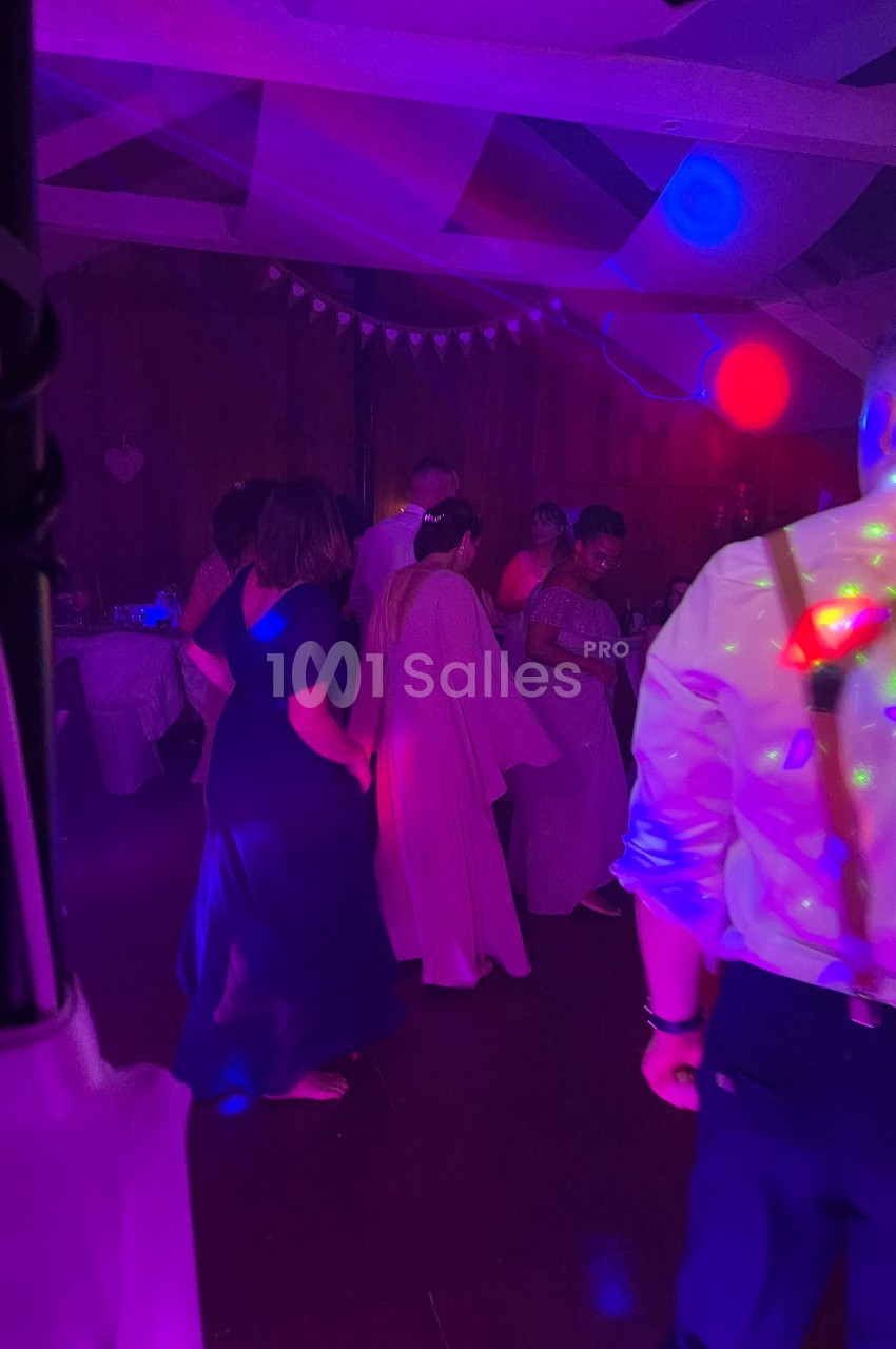 Des personnes dansent dans une salle faiblement éclairée avec des lumières colorées et une ambiance festive.