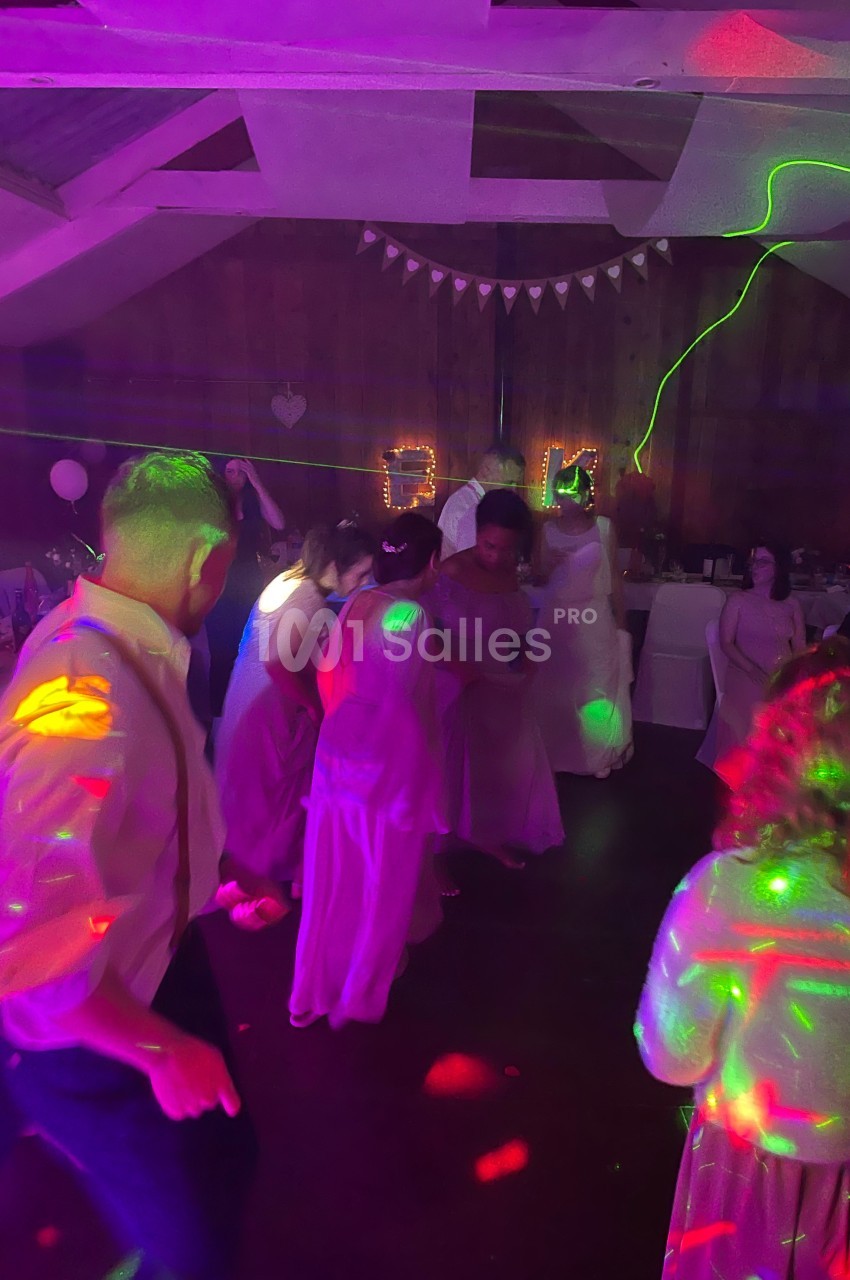 Personnes dansant sous des lumières colorées dans une salle décorée pour une fête ou un événement festif.