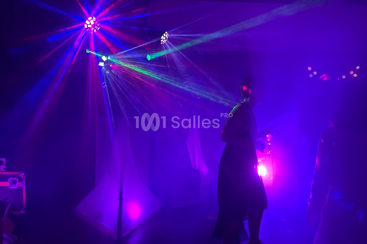 Personnes dansant sous des lumières colorées et des faisceaux lumineux dans une ambiance de soirée festive.