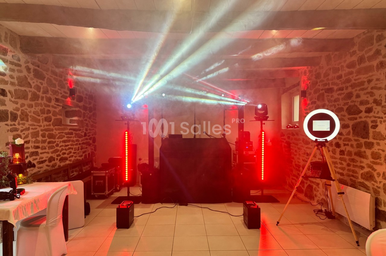 Installation de matériel de sonorisation et éclairage avec jeux de lumières dans une salle en pierre.