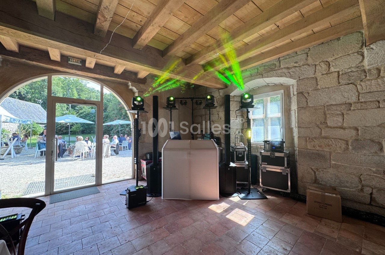 Installation de matériel de sonorisation et éclairage dans une salle en pierre avec vue sur une terrasse extérieure.
