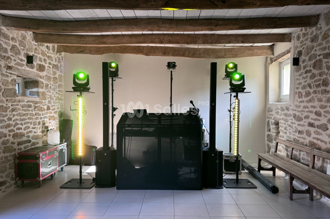 Installation de matériel de sonorisation et d'éclairage dans une salle en pierre avec poutres apparentes.