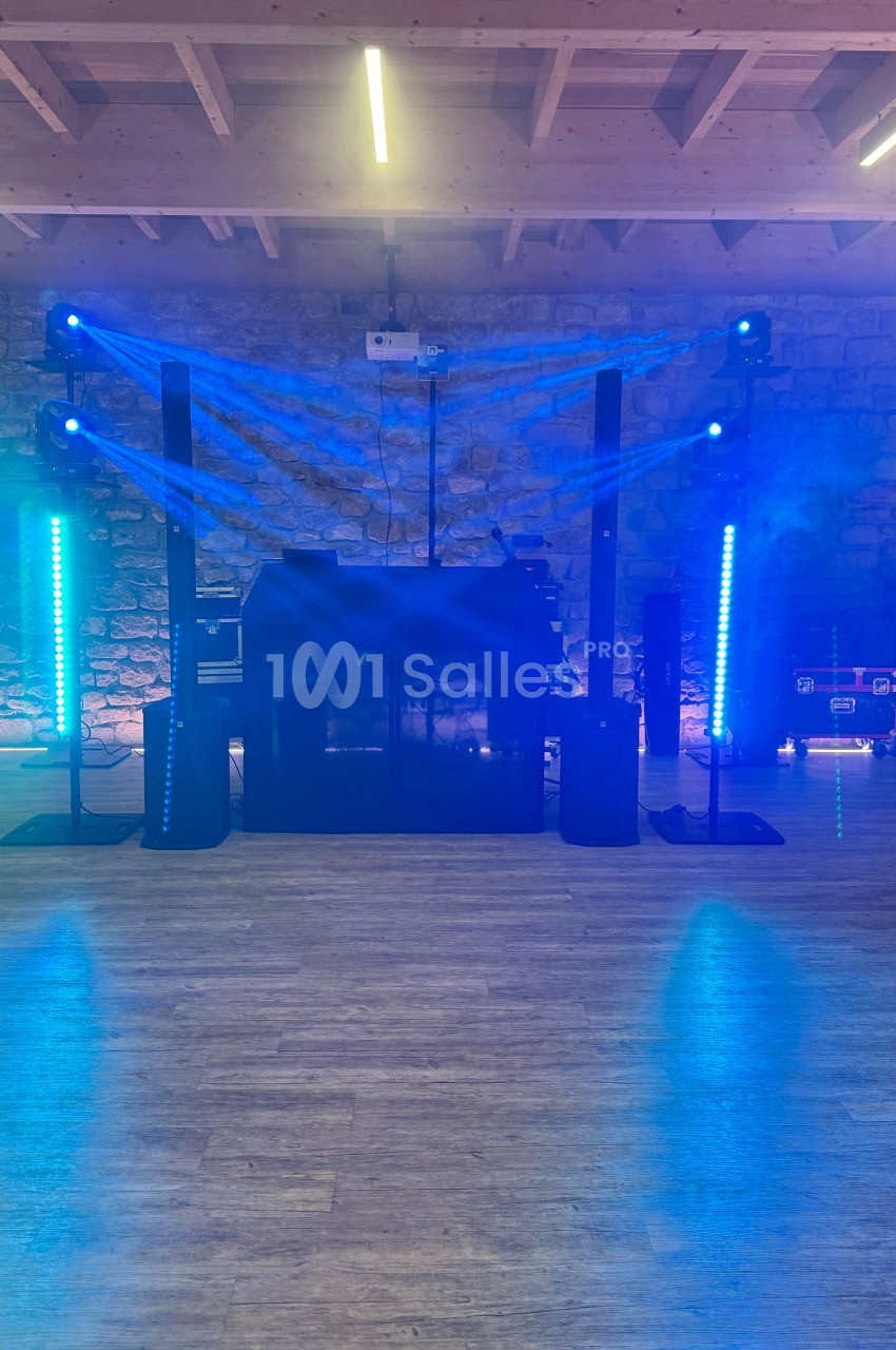 Installation de matériel de sonorisation et d'éclairage avec effets lumineux bleus dans une salle en pierre.