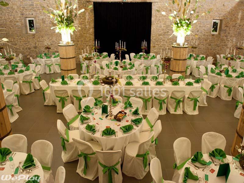 Salle de réception décorée avec des nappes blanches et des rubans verts, tables rondes et longues, ambiance élégante.