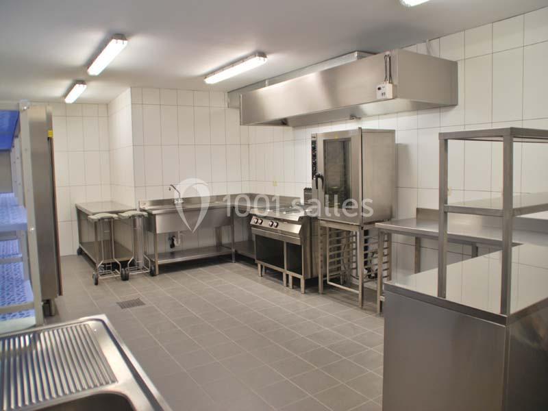Cuisine professionnelle avec équipements en inox, comprenant four, plaques de cuisson, plans de travail et évier.