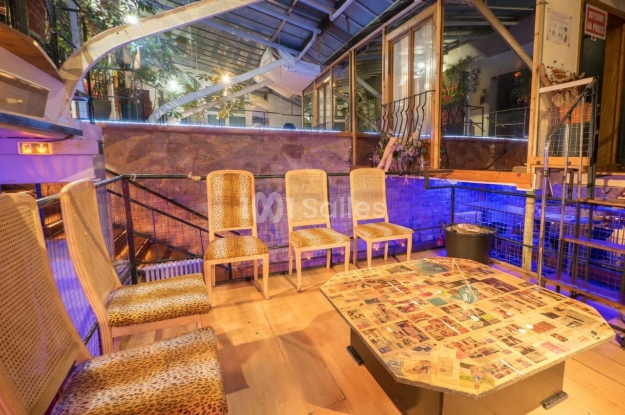 Salle lumineuse avec des chaises à motifs léopard autour d'une table basse décorée de coupures de journaux.
