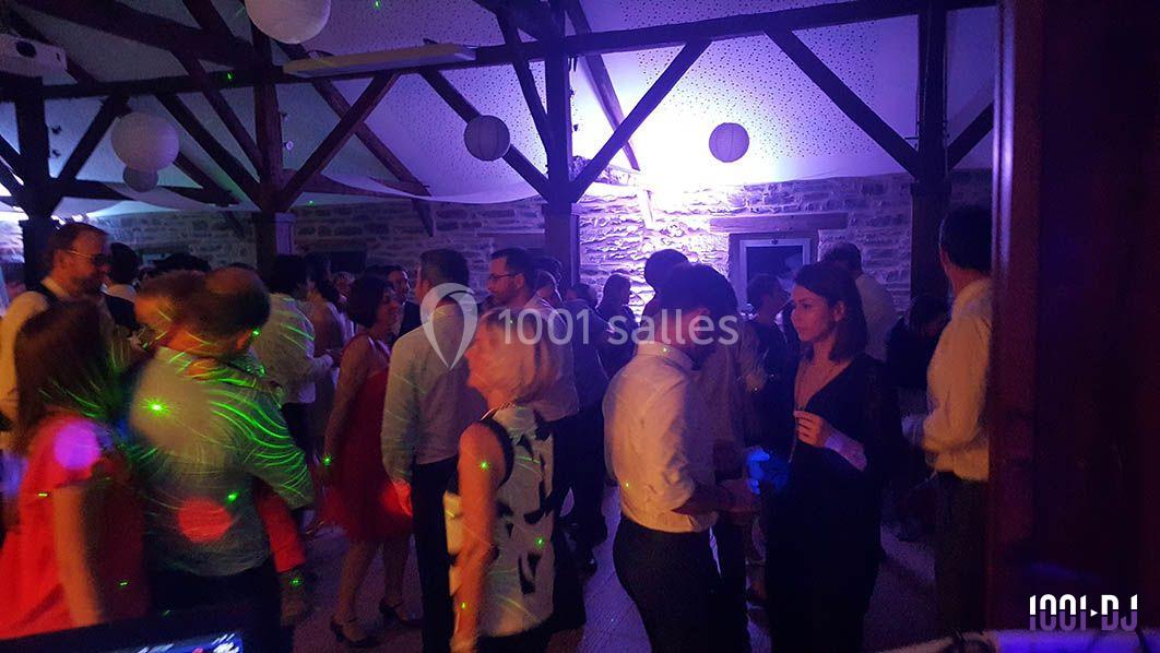 Personnes dansant et discutant lors d'une soirée festive dans une salle éclairée par des lumières colorées.
