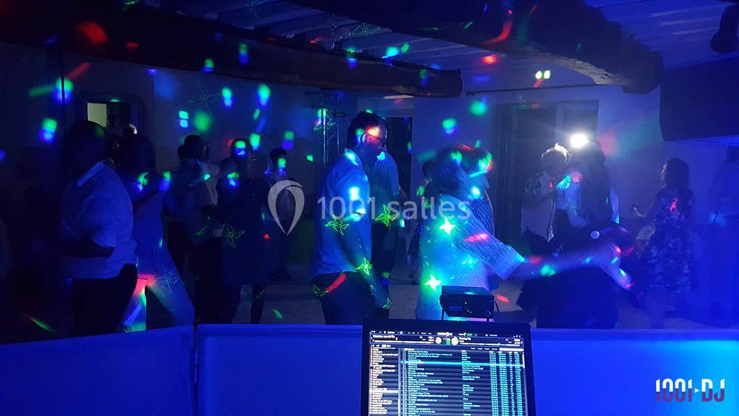 Personnes dansant sous des lumières colorées dans une salle sombre, vue depuis une table de mixage.