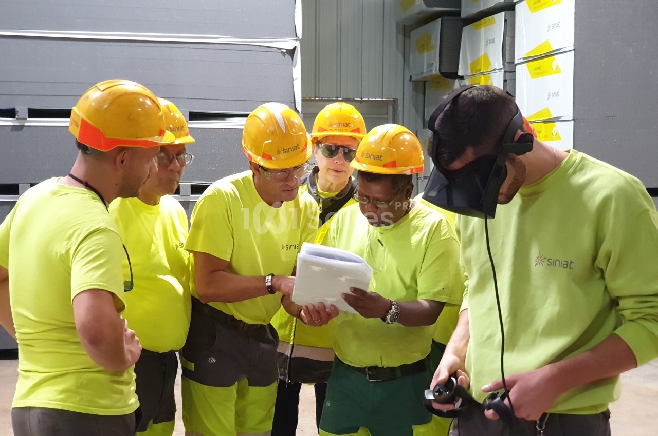 Des ouvriers en tenue de sécurité consultent un document dans un entrepôt industriel.