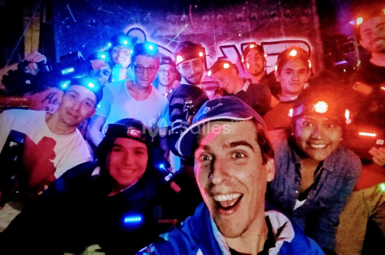 Un groupe de personnes souriantes portant des équipements lumineux dans un environnement sombre, probablement lors d'une…