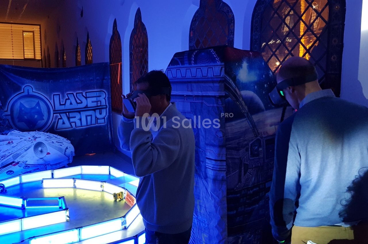 Deux personnes participent à une activité immersive de réalité virtuelle dans un décor futuriste éclairé.