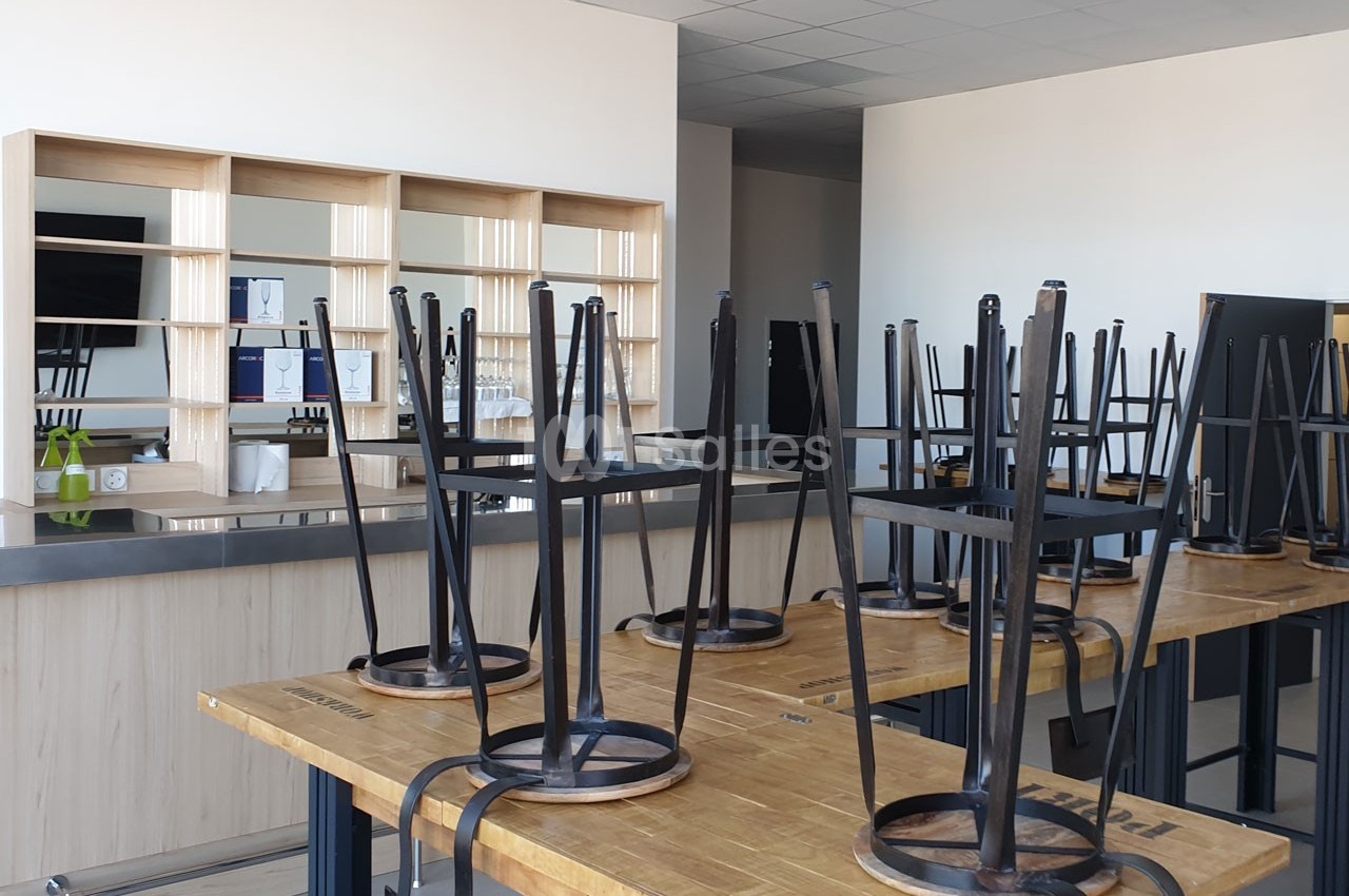 Chaises retournées sur des tables en bois dans une salle de classe ou de formation vide avec des étagères en arrière-plan.