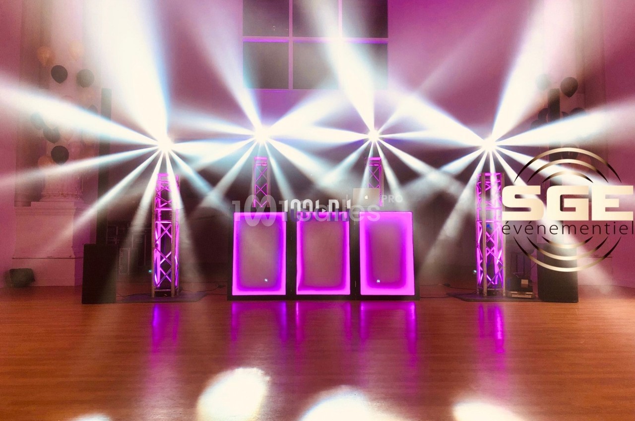 Installation lumineuse avec projecteurs LED colorés et panneaux lumineux violets dans une salle événementielle.