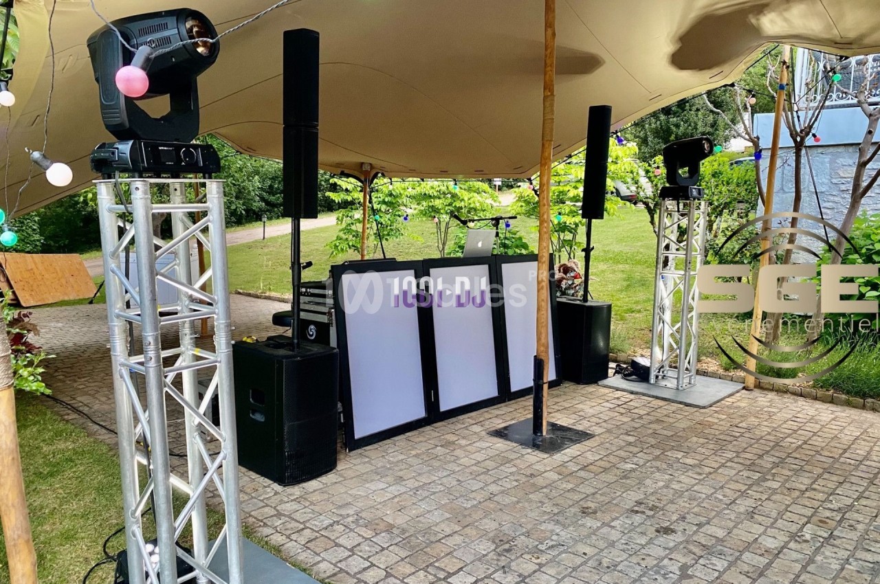 Installation de matériel de sonorisation et d'éclairage sous une tente, avec une table de mixage et des projecteurs.