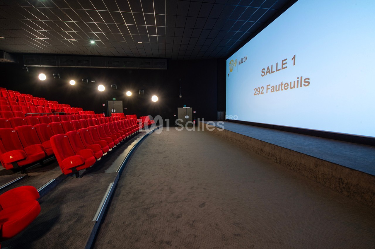Salle de cinéma vide avec des rangées de sièges rouges, un grand écran affichant ’Salle 1, 292 fauteuils’.
