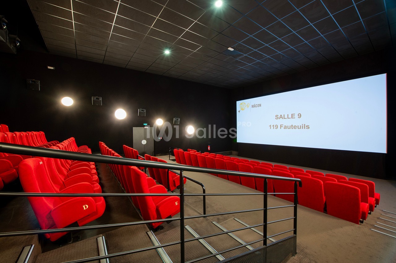 Salle de cinéma vide avec des sièges rouges, un écran affichant ’Salle 9, 119 fauteuils’ et un éclairage tamisé.
