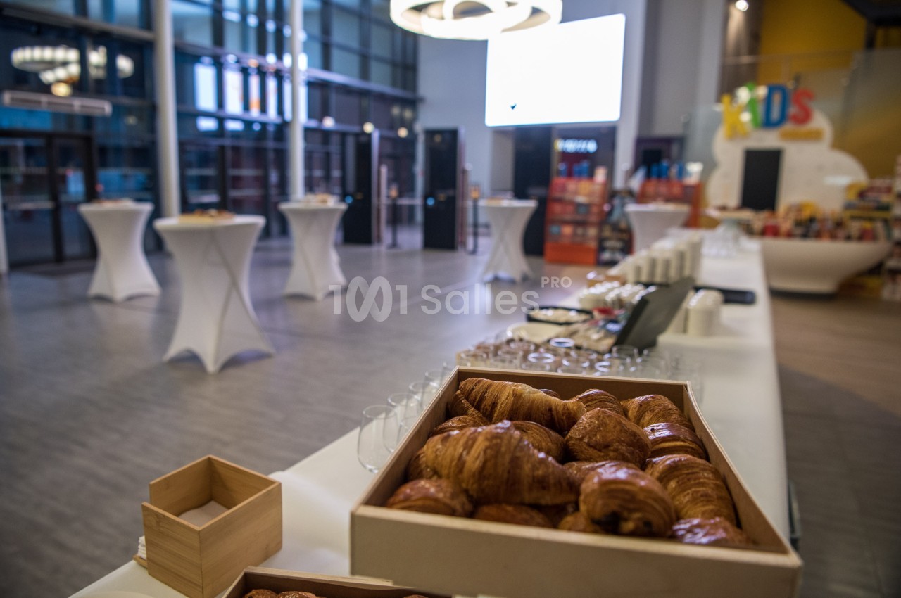Plateau de croissants sur une table dans une salle lumineuse avec des tables hautes et un espace de restauration en arrière…