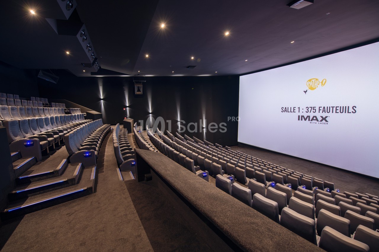 Salle de cinéma moderne avec sièges inclinés, écran géant et éclairage tamisé.