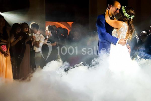 Un couple danse au milieu d'une piste entourée de fumée, sous le regard des invités.
