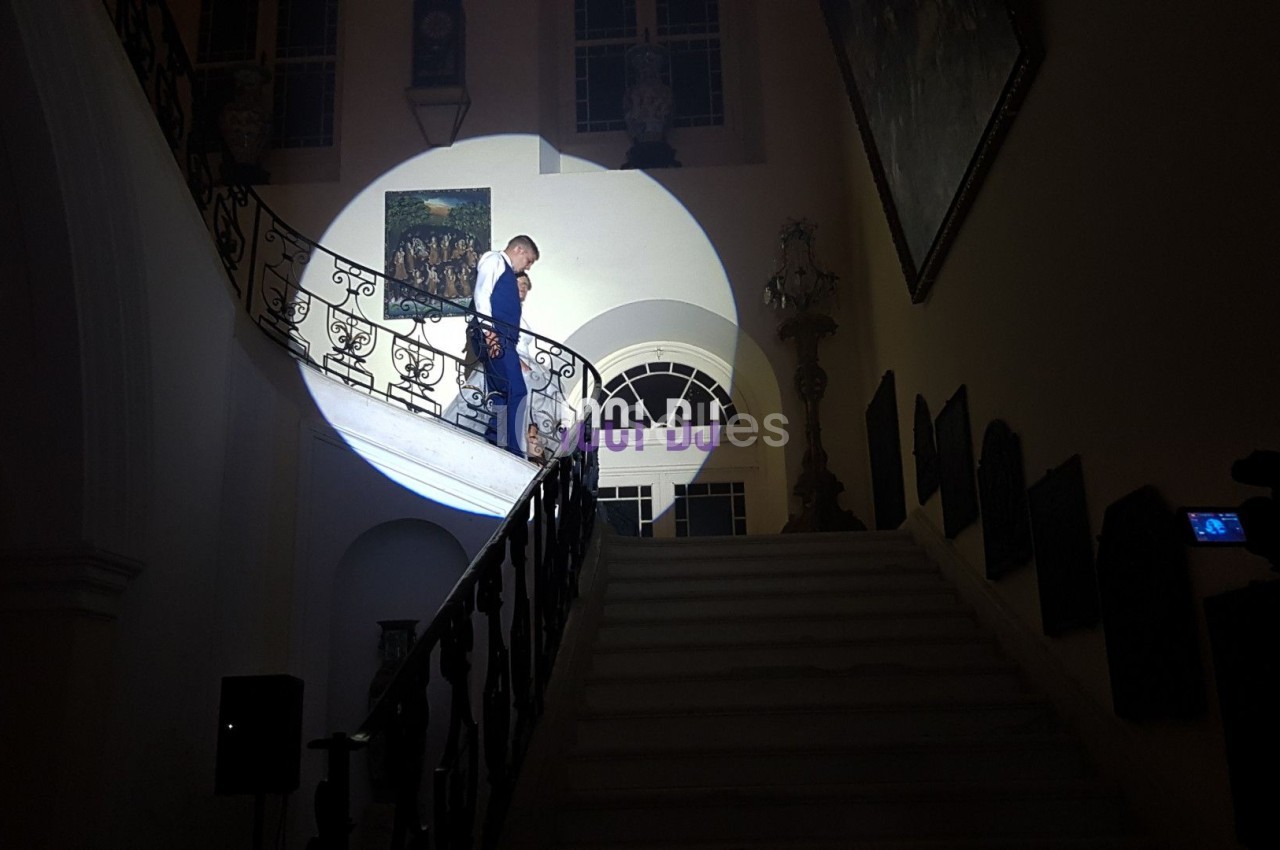 Un homme descend un escalier éclairé par un projecteur dans un intérieur sombre et élégant.