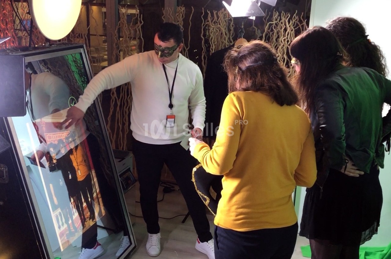 Un homme interagit avec un miroir interactif entouré de trois personnes dans un espace éclairé.