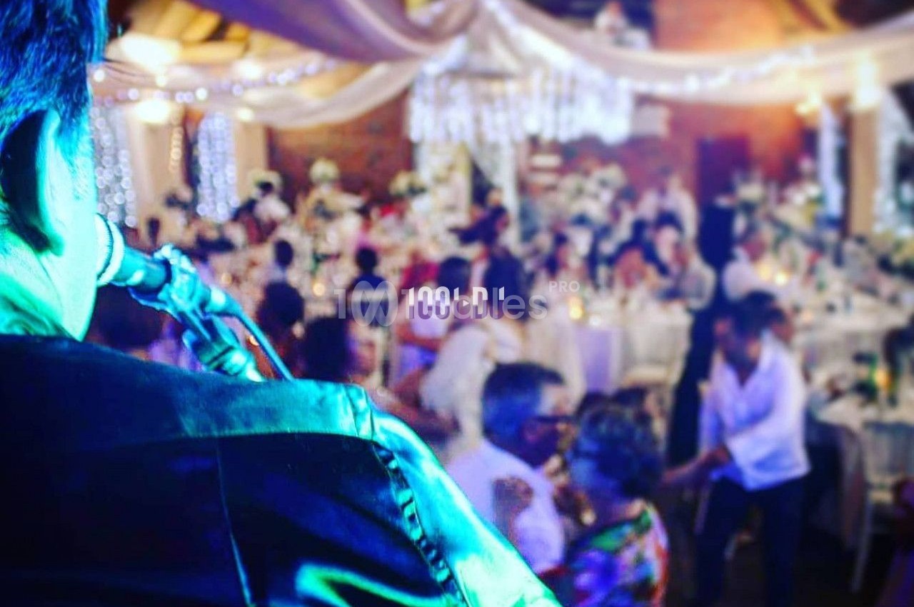 Un musicien joue du saxophone lors d'une réception festive dans une salle décorée avec des lumières et des drapés.