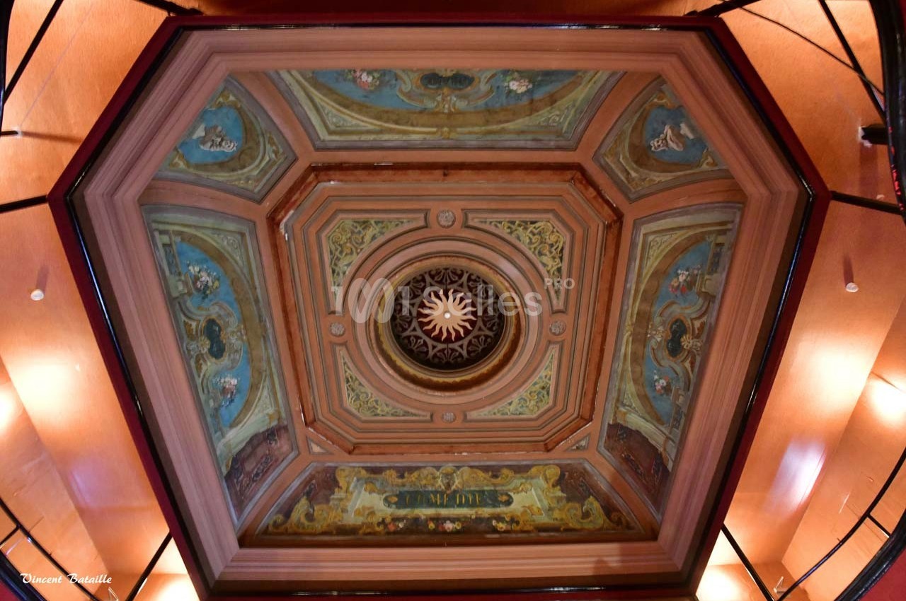 Plafond hexagonal décoré de fresques colorées et d'un motif central en forme de soleil entouré d'ornements.