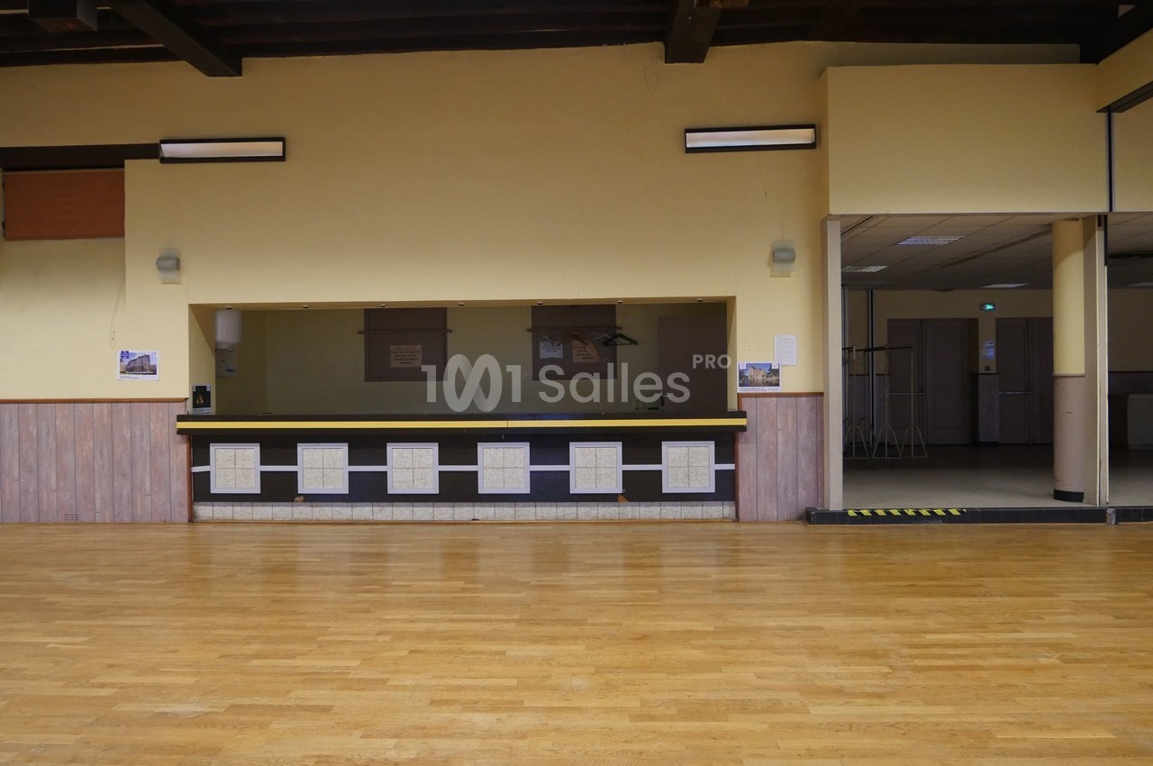 Salle avec parquet en bois, comptoir central carrelé et murs clairs, éclairée par des appliques murales.