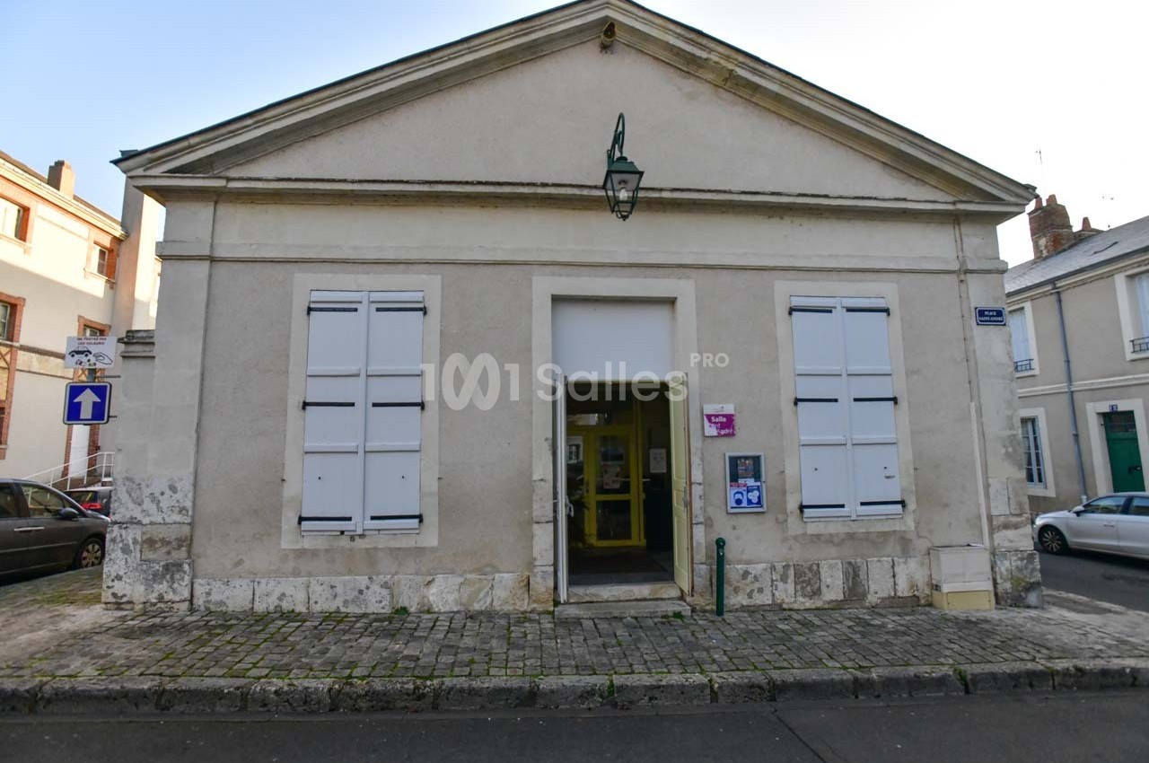 Façade d'un bâtiment ancien avec des volets fermés, une porte centrale ouverte et une lanterne suspendue.