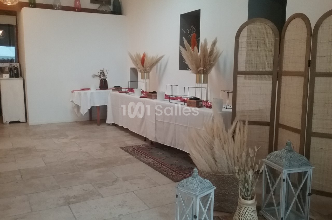 Salle décorée avec des tables couvertes de nappes blanches, ornées de bouquets de pampas et de lanternes décoratives.