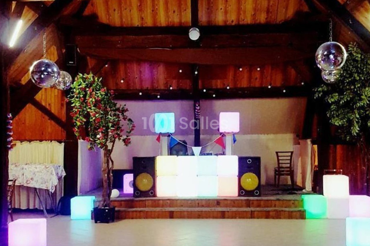 Salle décorée avec des cubes lumineux colorés, une estrade avec matériel de sonorisation et des boules à facettes suspendues.