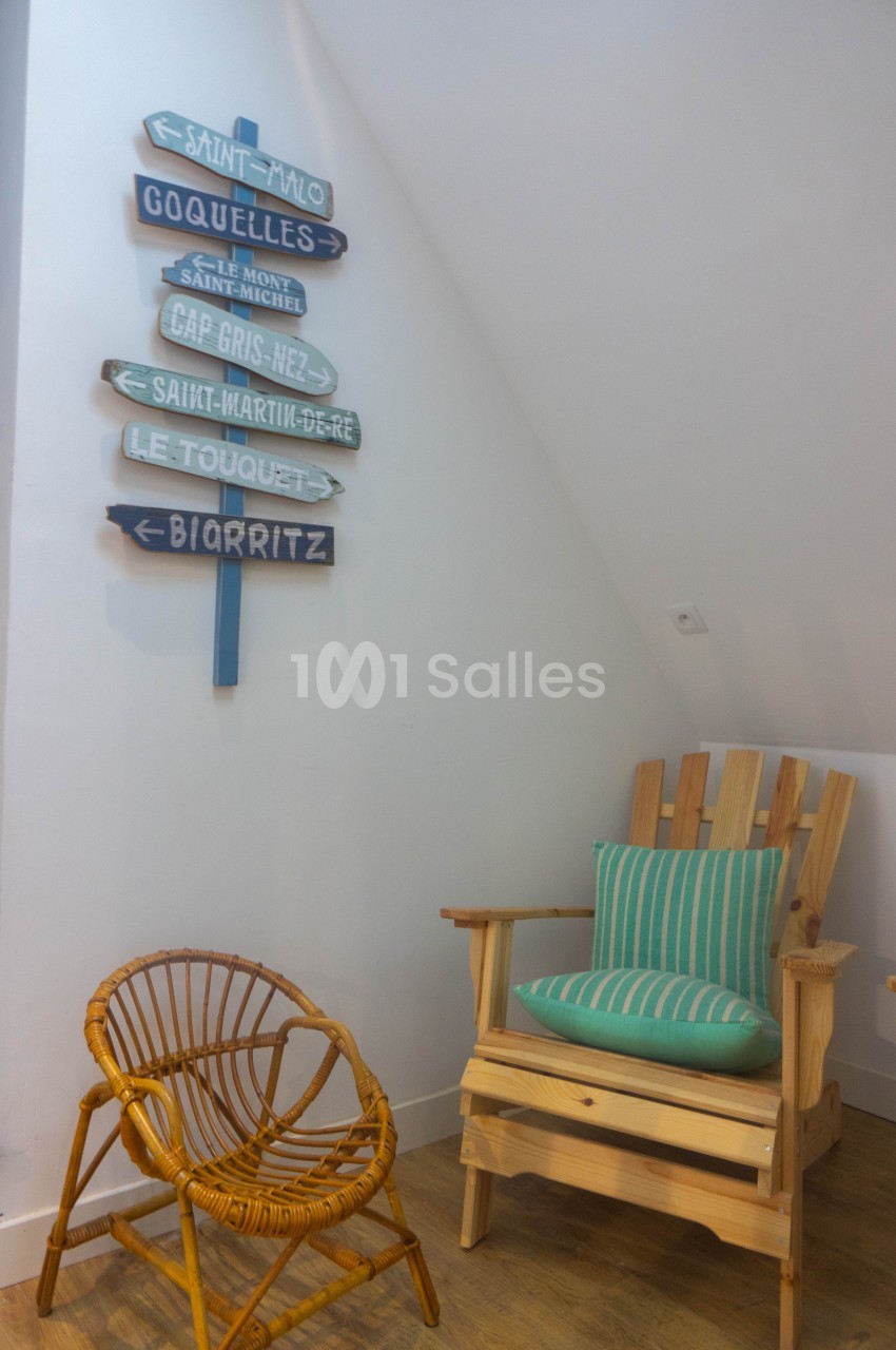 Deux fauteuils en bois, dont un avec coussin rayé, près d'un mur décoré de panneaux directionnels colorés.