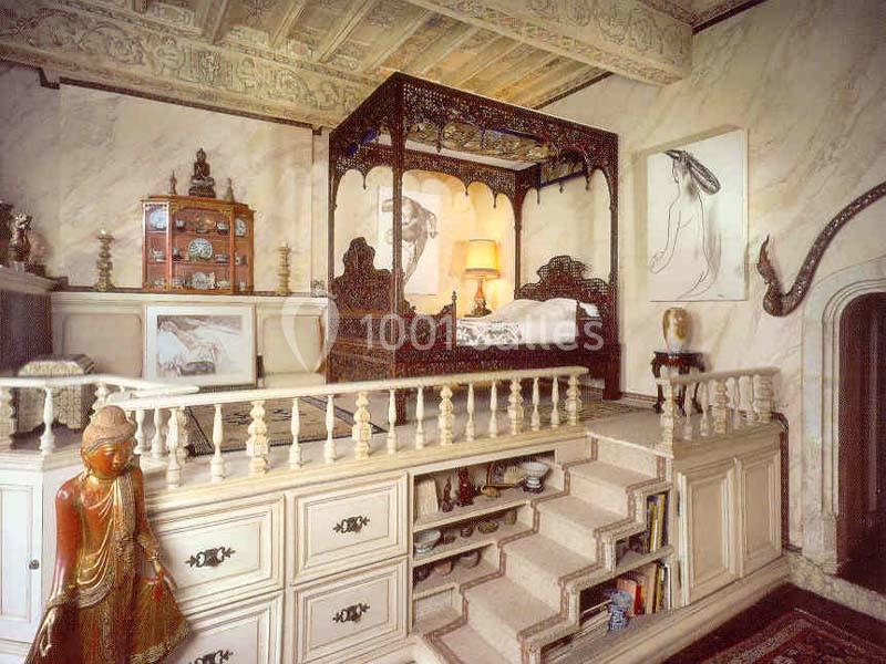 Chambre décorée avec un lit à baldaquin sculpté, statues bouddhistes et mobilier en bois dans un style traditionnel.