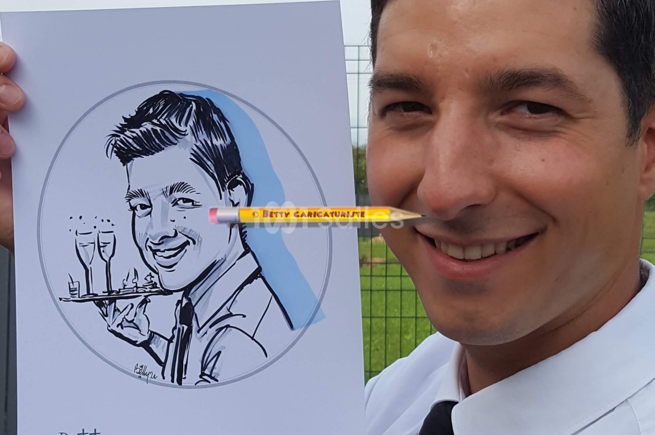 Un homme souriant tient un dessin caricatural de lui-même, réalisé avec des détails humoristiques.