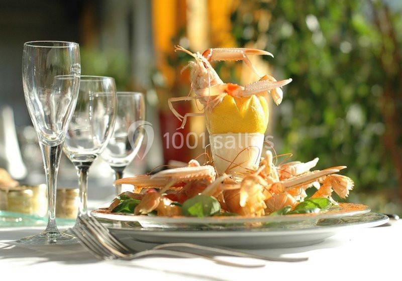 Assiette de langoustines dressées autour d'un citron, servie sur une table avec des couverts et des verres à vin.