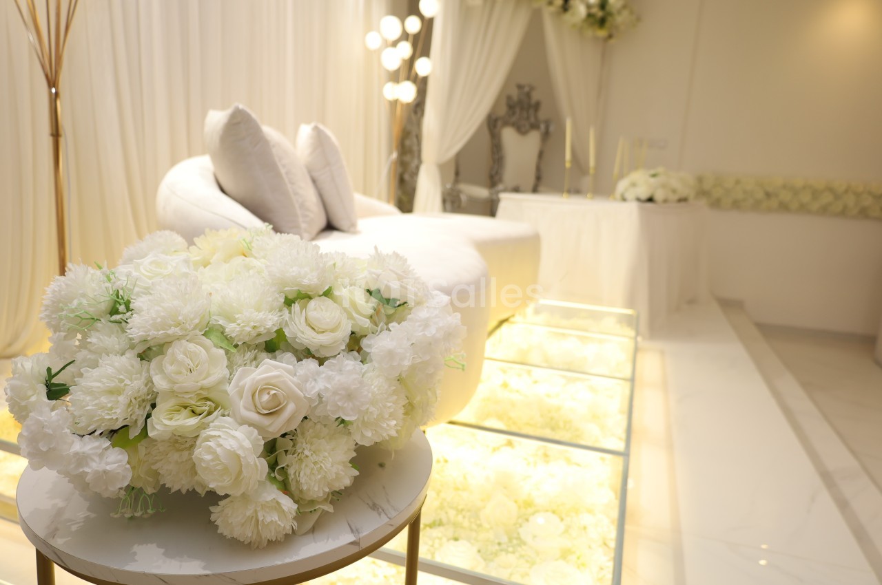 Bouquet de fleurs blanches sur une table ronde devant un salon décoré dans des tons clairs et élégants.