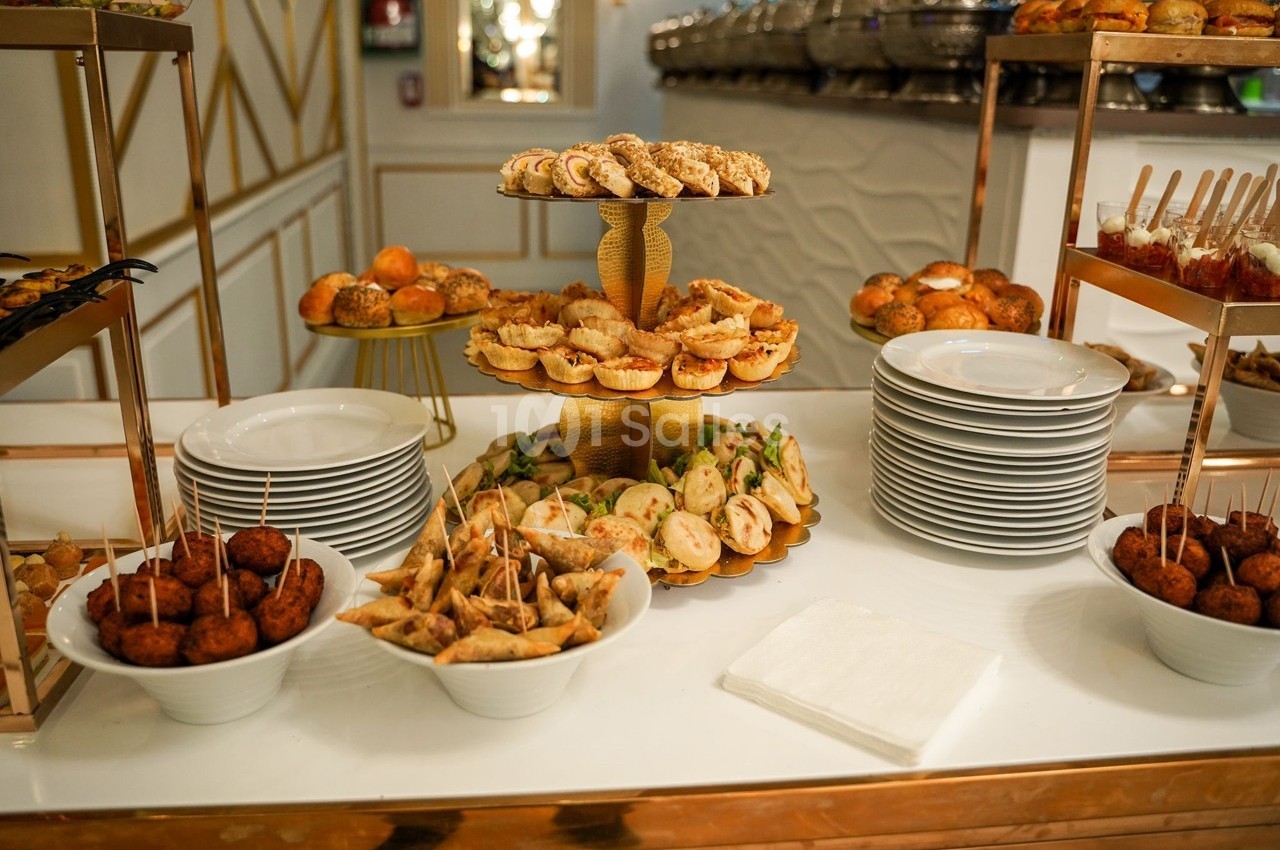 Buffet avec des assiettes empilées et une variété de bouchées salées présentées sur des plateaux et dans des bols.