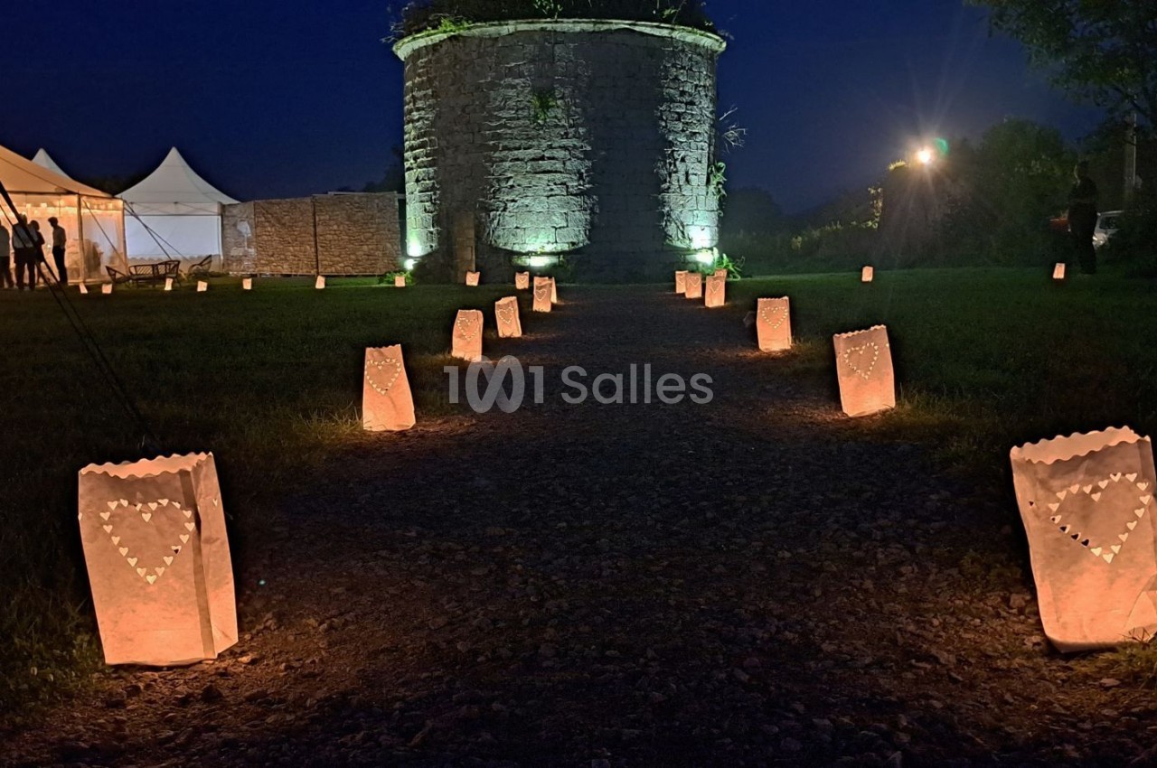 Chemin éclairé par des lanternes en papier décorées de cœurs, menant à une tour illuminée de nuit.