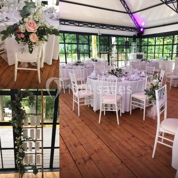 Salle de réception décorée avec des tables rondes, chaises blanches et arrangements floraux élégants.