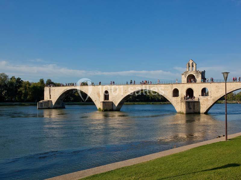 Pont en pierre à arches traversant une rivière, avec des visiteurs et un ciel dégagé en arrière-plan.