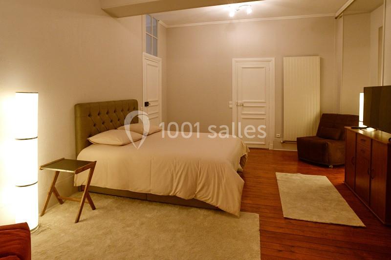 Chambre spacieuse avec lit double, parquet en bois, éclairage doux et mobilier minimaliste.