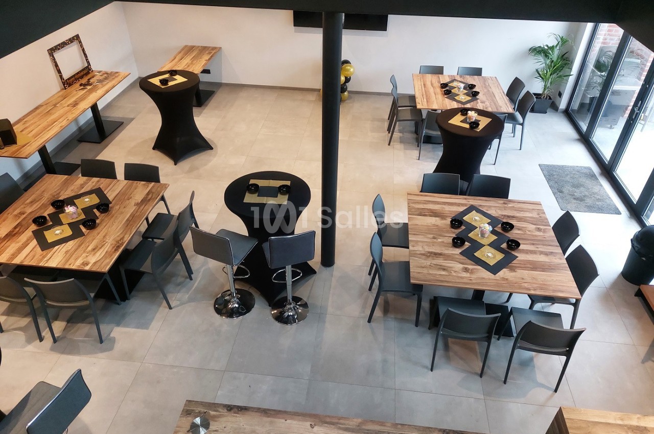 Salle moderne avec tables en bois, chaises grises et tables hautes, vue d'ensemble depuis un angle en hauteur.