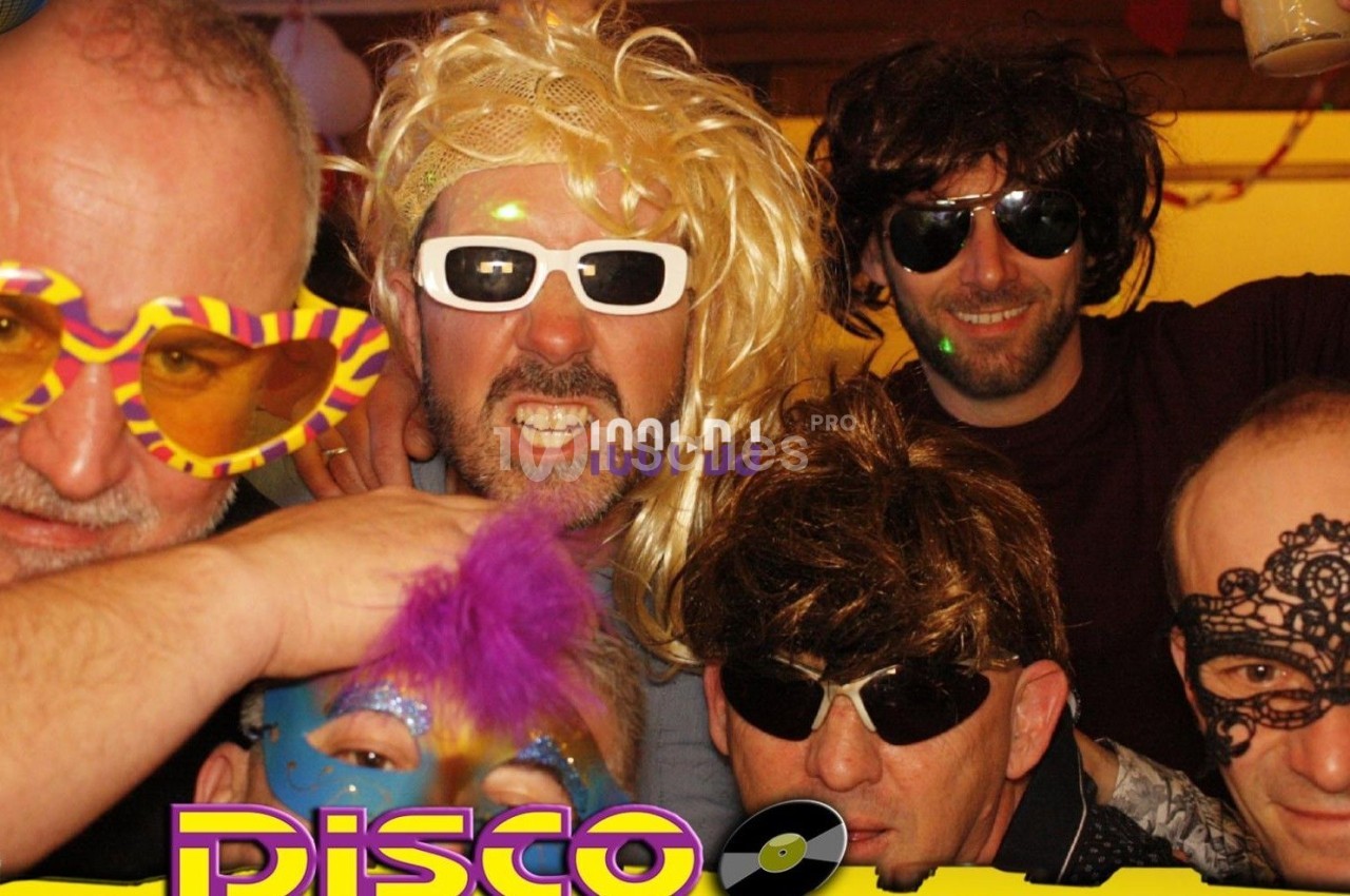 Des personnes déguisées avec perruques, lunettes et masques dans une ambiance festive sur le thème disco.