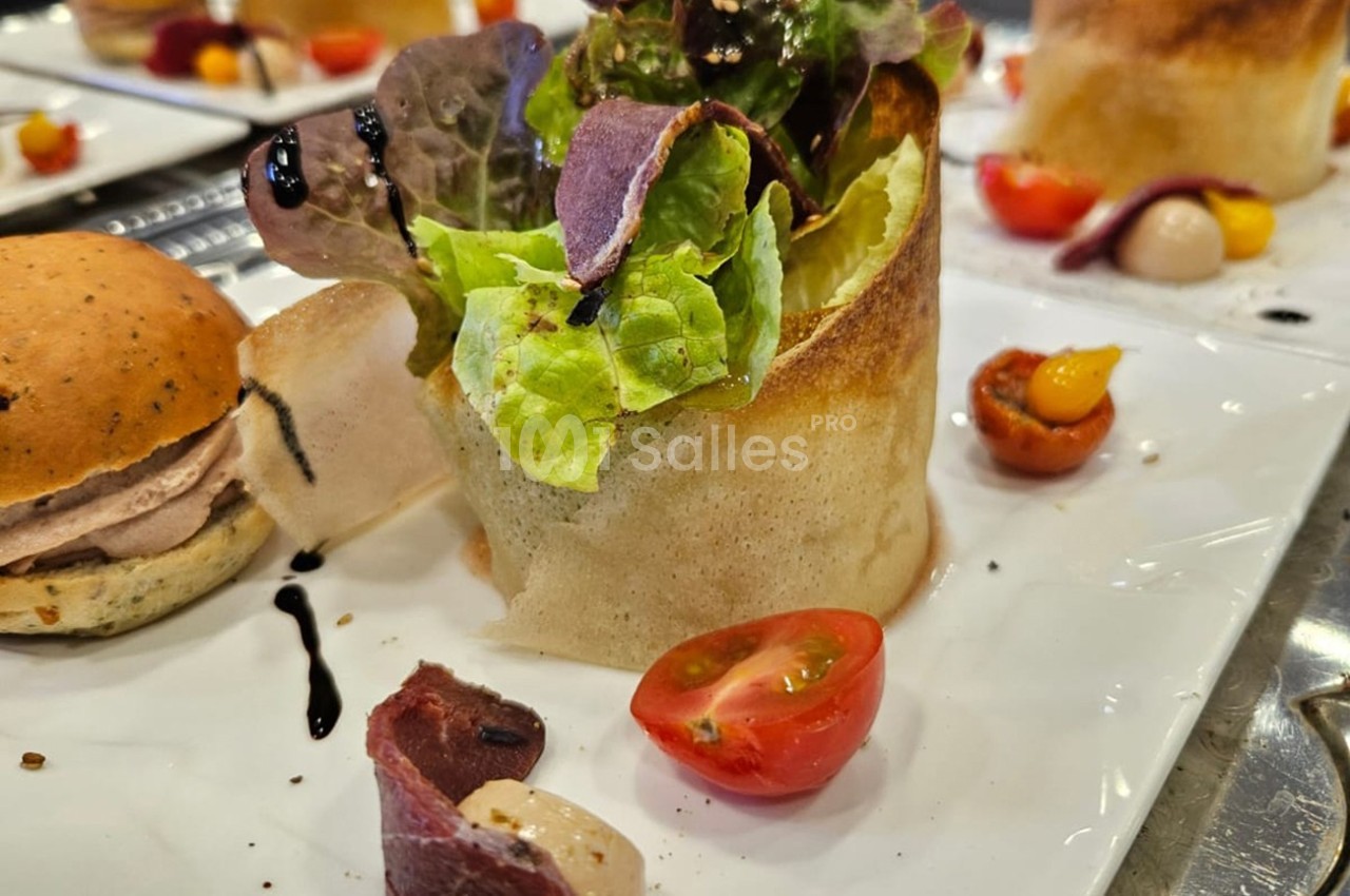 Assiette composée d'une salade en corolle de pâte croustillante, tomates cerises et garnitures variées.