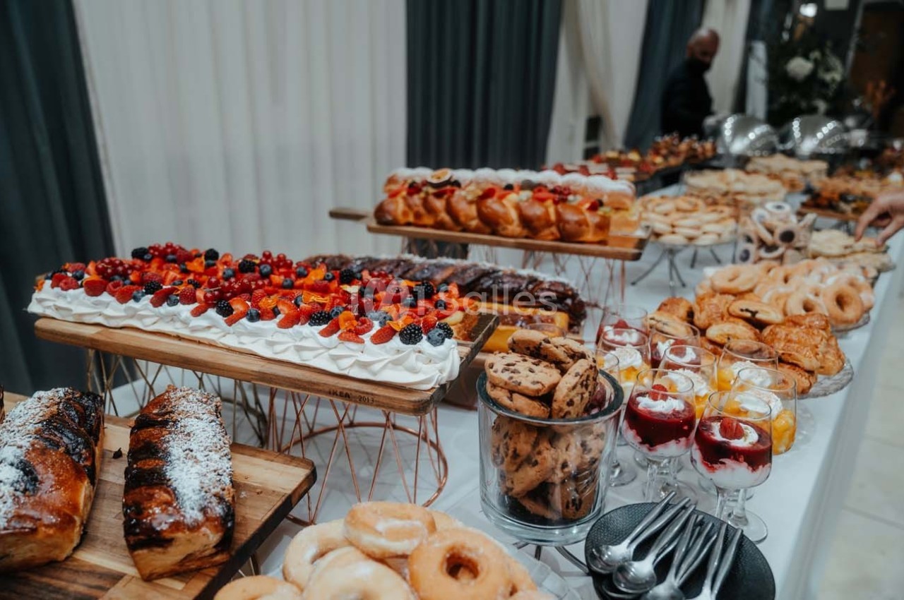 Table garnie de desserts variés, incluant gâteaux, tartes aux fruits, biscuits, verrines et viennoiseries.