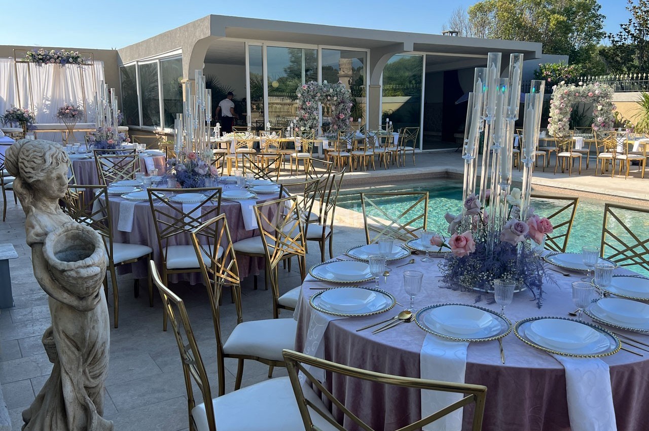 Tables élégamment dressées avec des décorations florales près d'une piscine, dans un espace extérieur moderne.