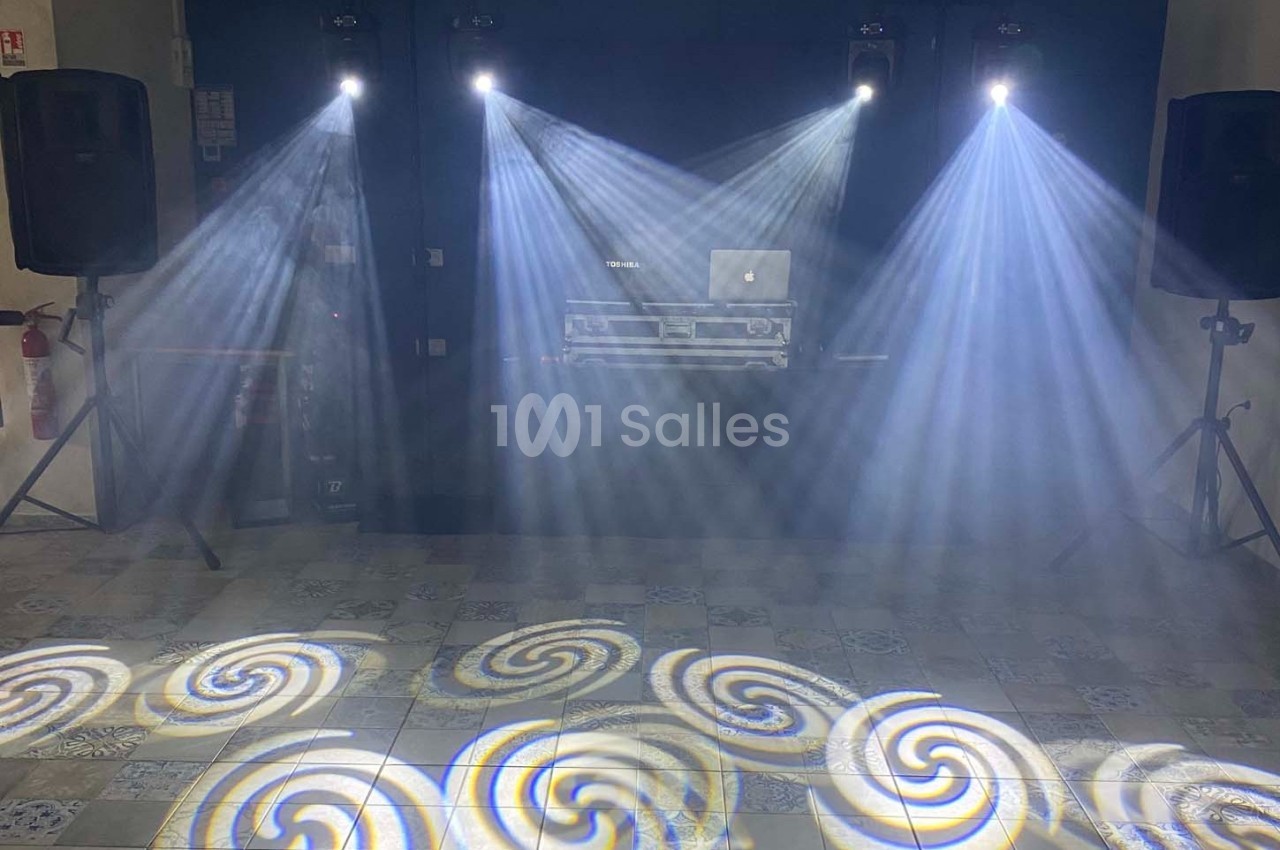 Effets lumineux avec faisceaux blancs et motifs circulaires projetés sur le sol dans une salle équipée de haut-parleurs.