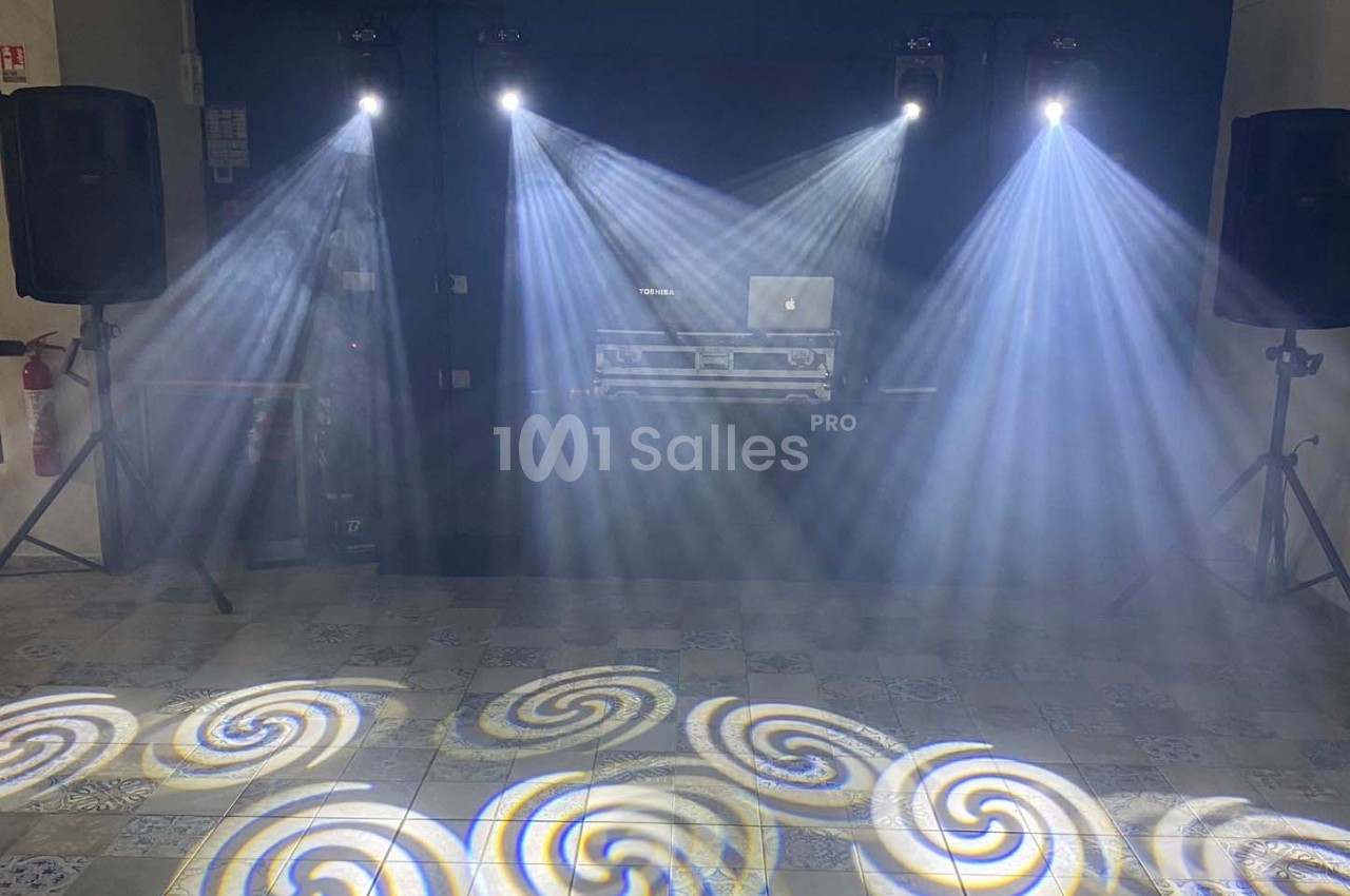 Jeux de lumières projetant des motifs en spirale sur un sol carrelé, avec une table de mixage en arrière-plan.